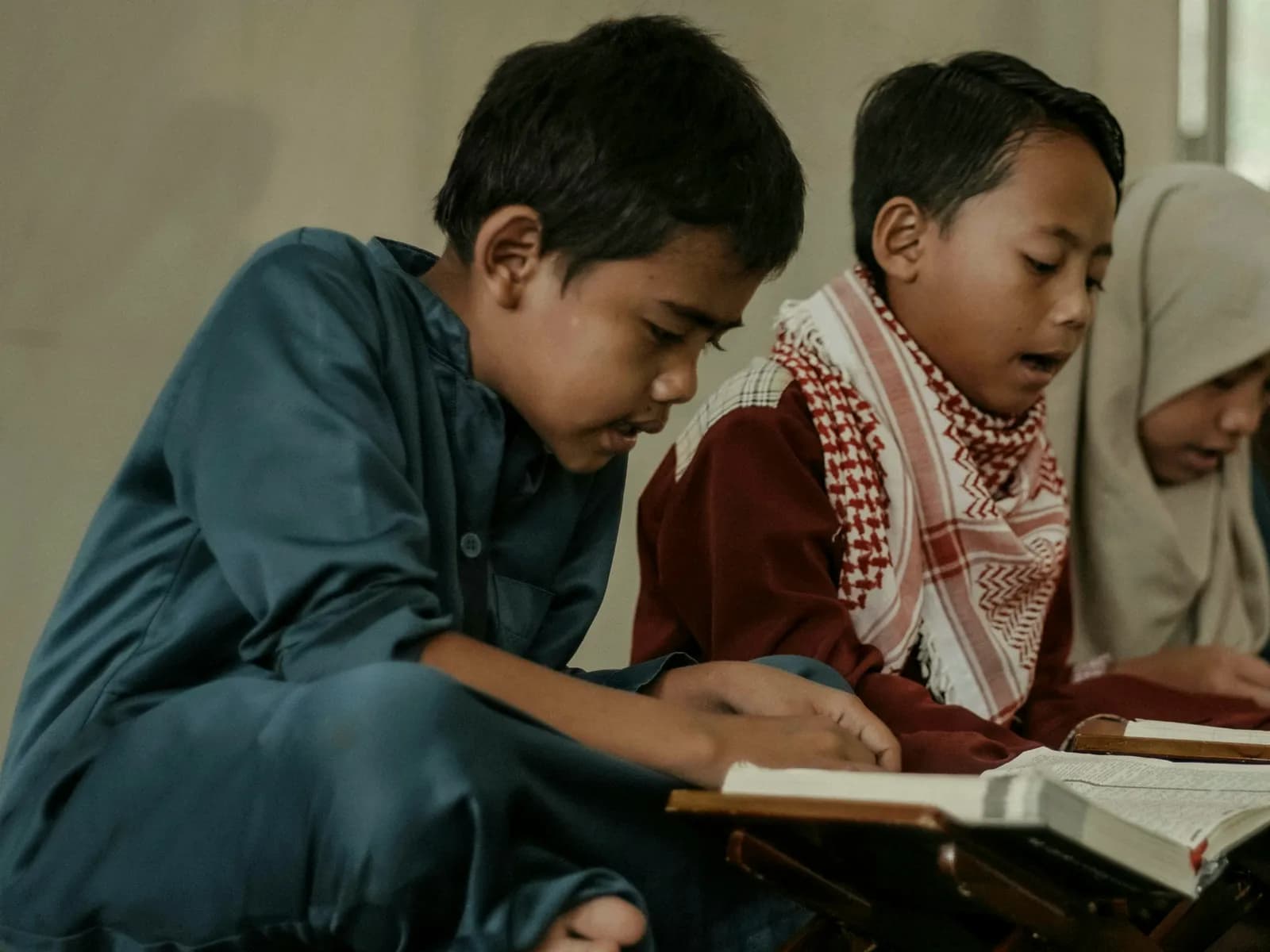 Children reading the Quran together from a shared stand