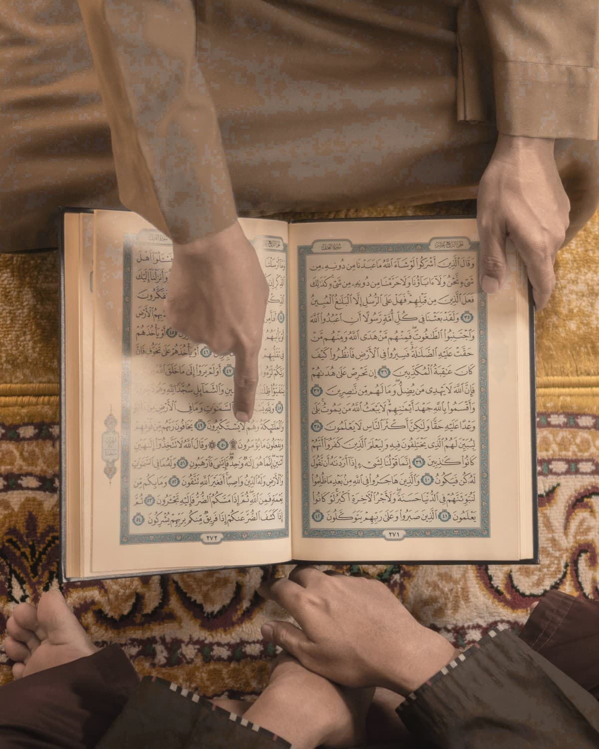Teacher pointing to a verse while a student follows along in the Quran